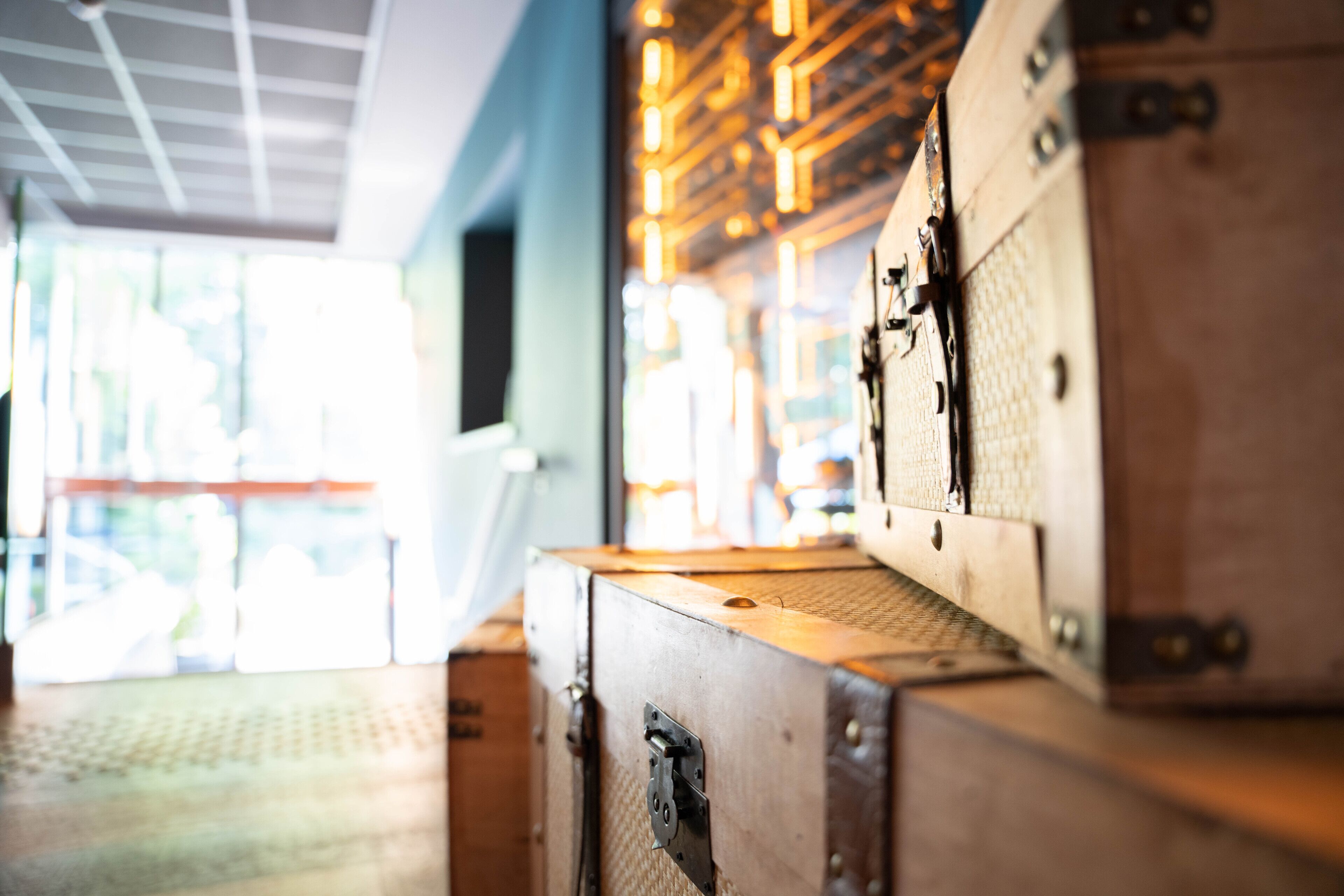 A close-up of vintage suitcases stacked indoors with a modern ceiling and natural light coming through a window.