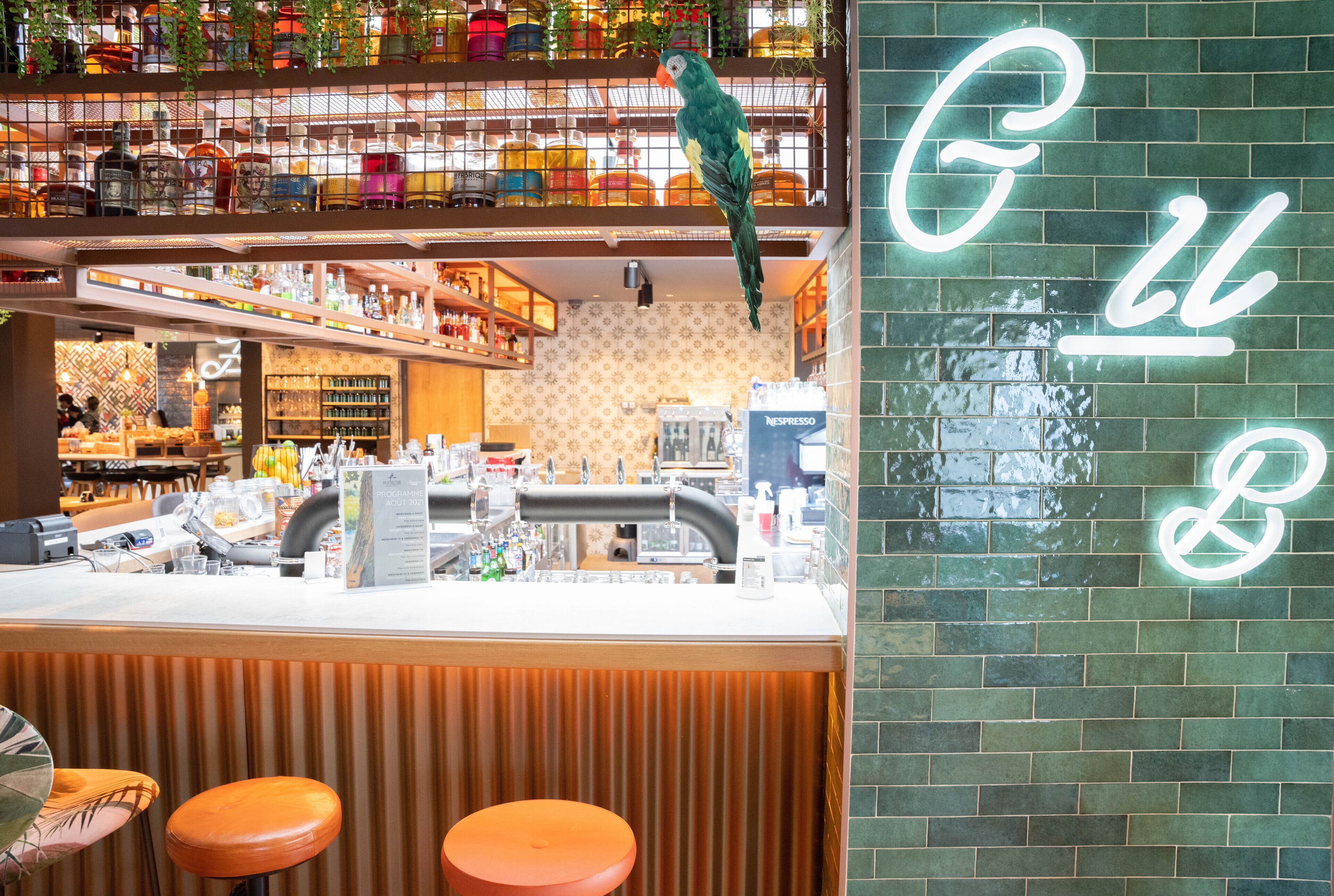 A bar with a neon sign, a parrot, and a counter with stools.