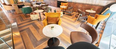Un espace de détente moderne, avec des canapés, des tables et un écran de télévision.