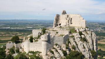 Un castillo de piedra histórico en una colina rocosa, con una vista panorámica del campo.