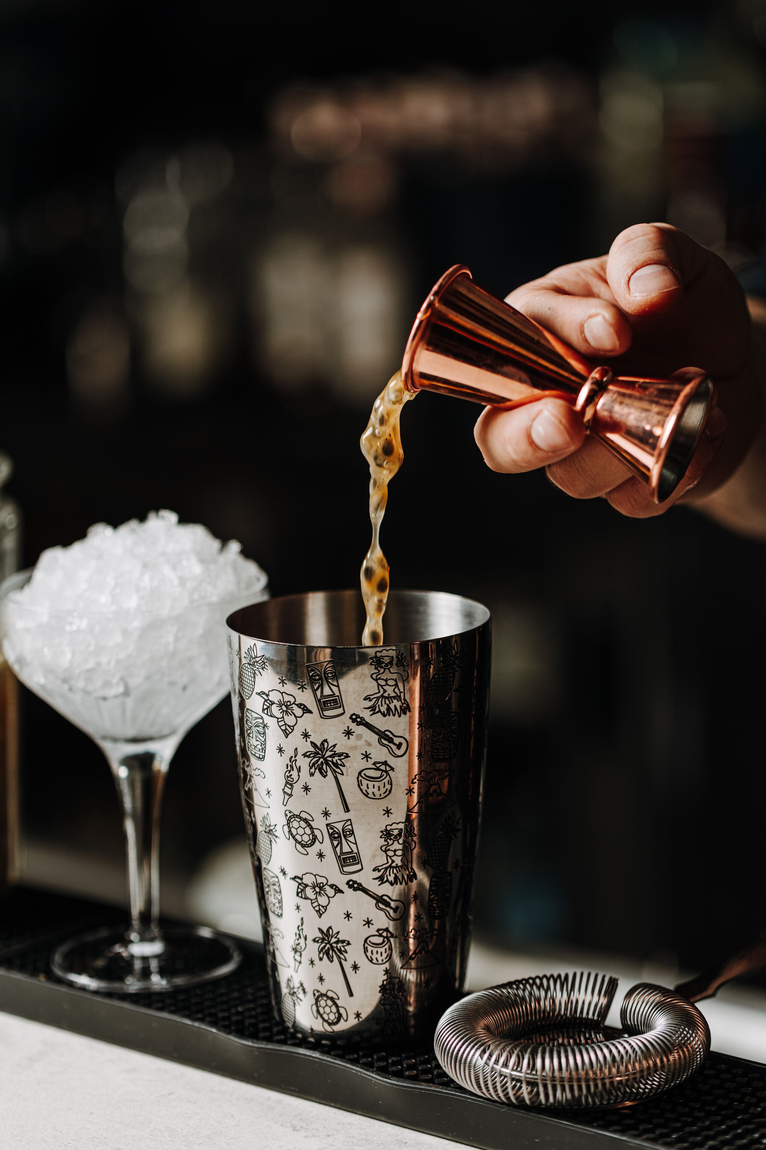 En hånd hælder væske i en cocktailshaker.