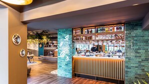 Una zona de bar con una barra, estantes llenos de botellas y una persona trabajando detrás.