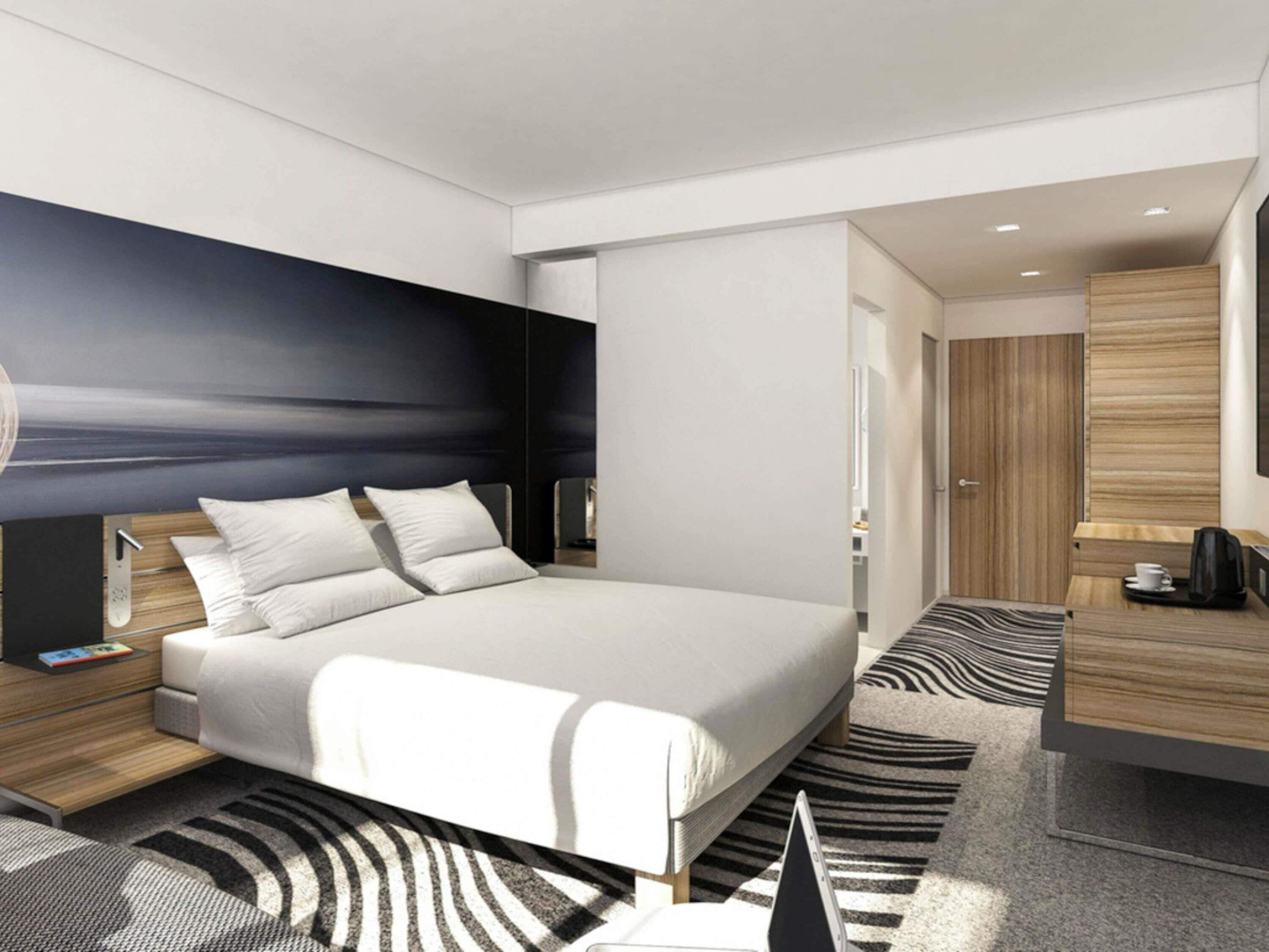 Una habitación de hotel moderna con una cama grande, mesitas de noche, un escritorio y un armario.