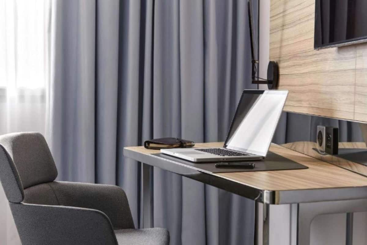 Una habitación moderna con escritorio, silla, laptop y un altavoz.