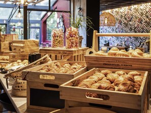 Cajas de madera llenas de pasteles y pan, dispuestas sobre una mesa en una tienda.