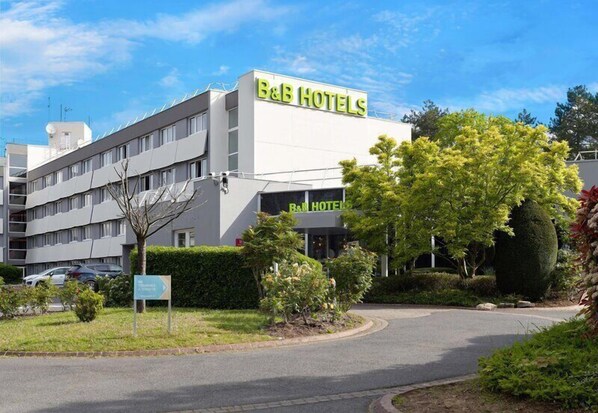 A B&B hotel with a modern design, a parking lot, and well-maintained landscaping.