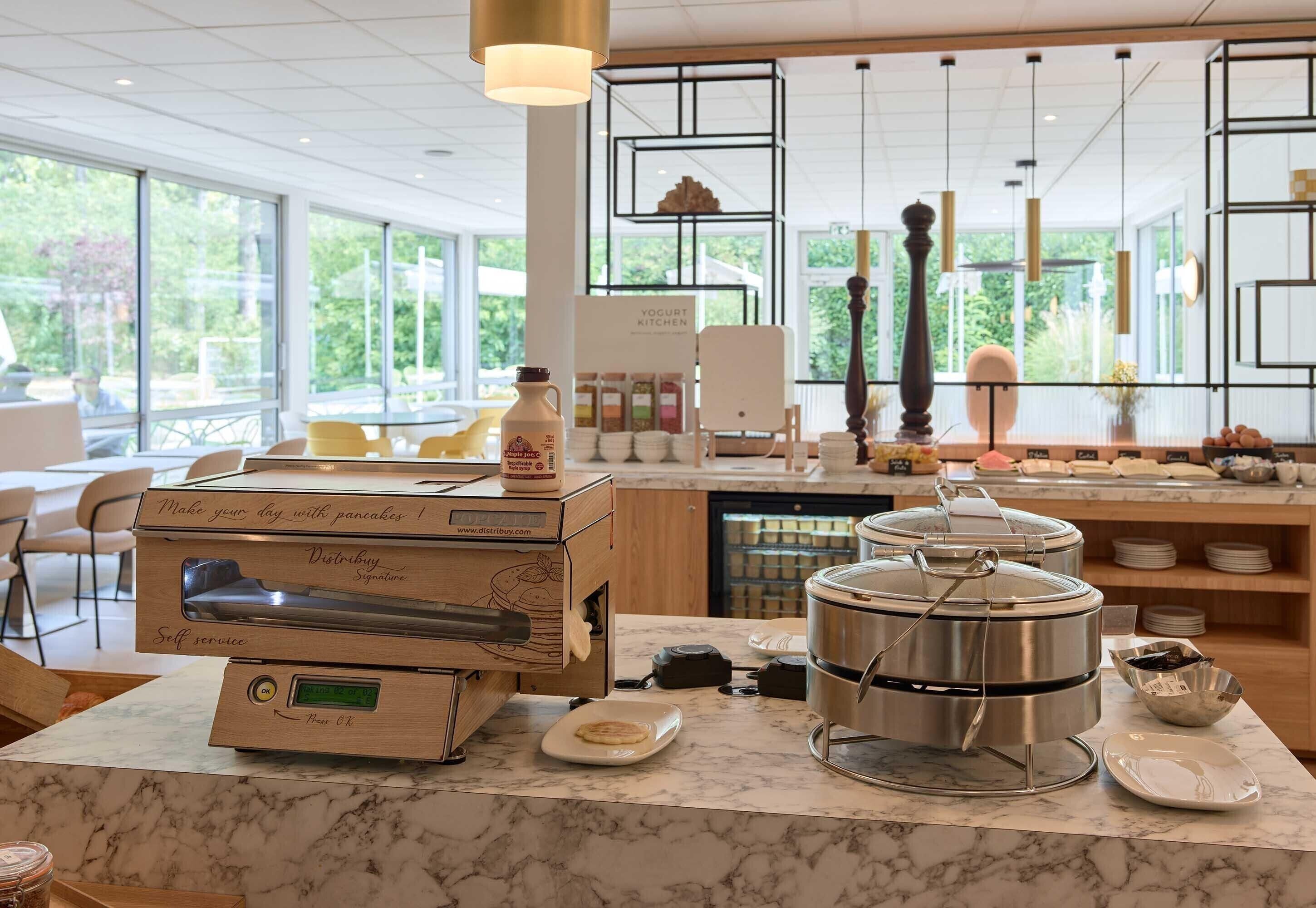 A self-service breakfast station with a coffee machine, a yogurt dispenser, and a large pot on the counter.