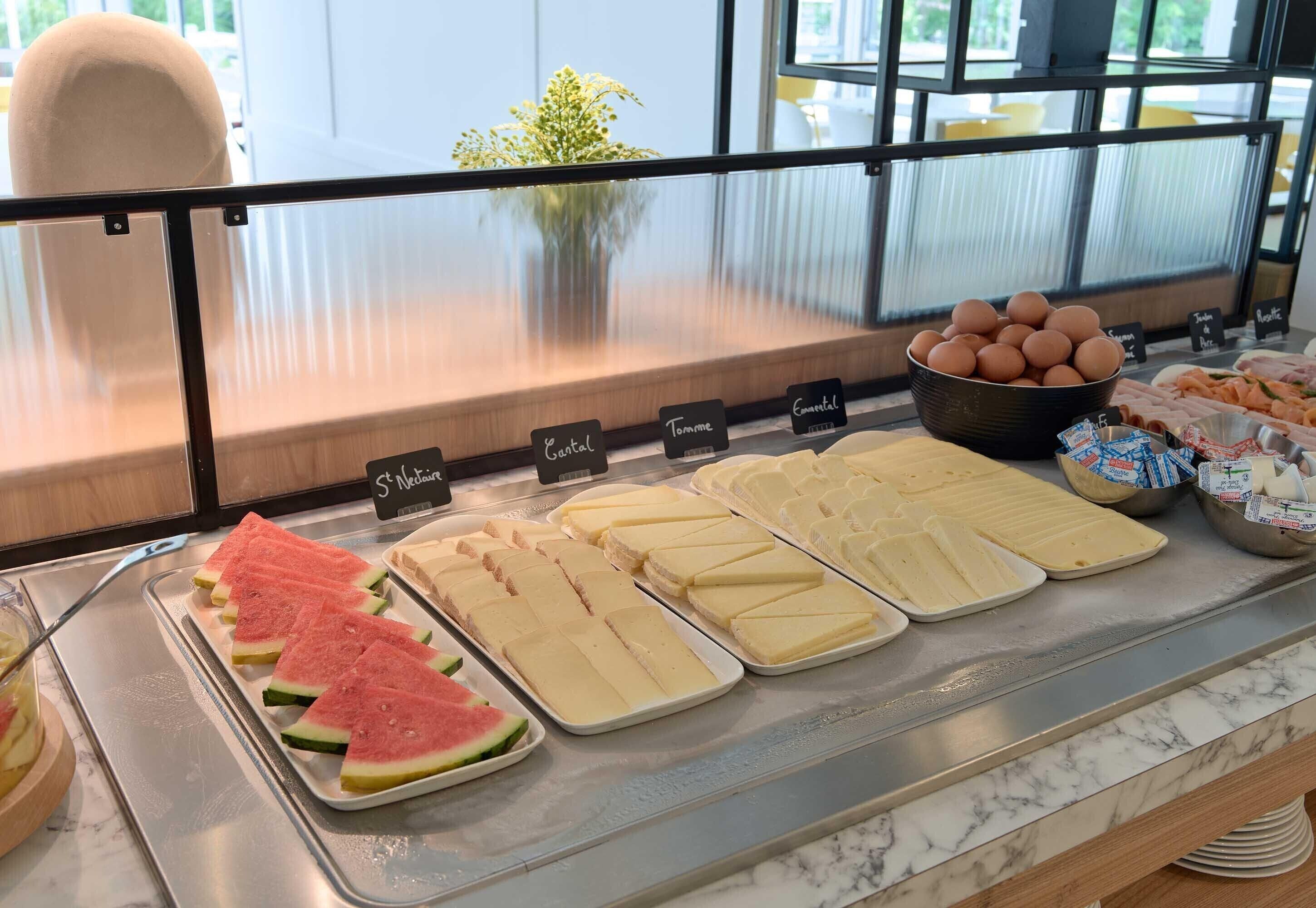 A buffet with various food items including watermelon slices, cheese, and eggs.