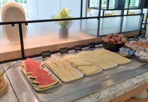 Un bufé con diferentes opciones de comida, incluyendo rebanadas de sandía, queso y huevos.