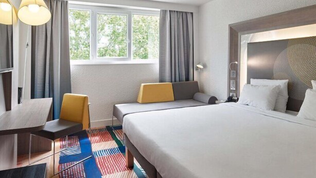 A hotel room with a large bed, two bedside tables, a desk, and a chair. - B&B HOTEL Cergy Port (Cergy)