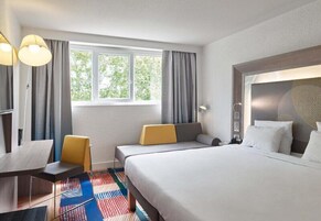 Una habitación de hotel con una cama grande, dos mesitas de noche, un escritorio y una silla.