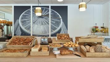 A breakfast buffet with various baked goods and a large clock in the background.