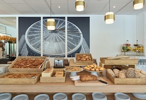 Un bufé de desayuno con diversos productos horneados y un gran reloj de fondo.