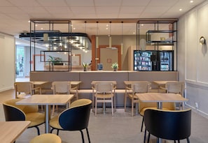 A modern cafe interior with a bar area, seating, and a refrigerator. - B&B HOTEL Cergy Port (Cergy)