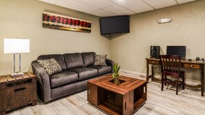 A living room with a sofa, coffee table, TV, desk, and chair. - Quality Inn & Suites Winfield (Winfield)