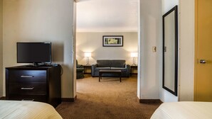 A hotel room with a bed, a TV, a sofa, a coffee table, and a framed picture on the wall. - Quality Inn & Suites Winfield (Winfield)