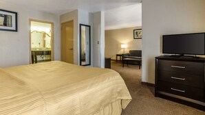A hotel room with a bed, a TV, a desk, and a chair. - Quality Inn & Suites Winfield (Winfield)