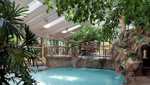 An indoor pool with a waterfall, surrounded by stone walls and a wooden deck. - The Park Vista - a DoubleTree by Hilton Hotel - Gatlinburg (Gatlinburg)
