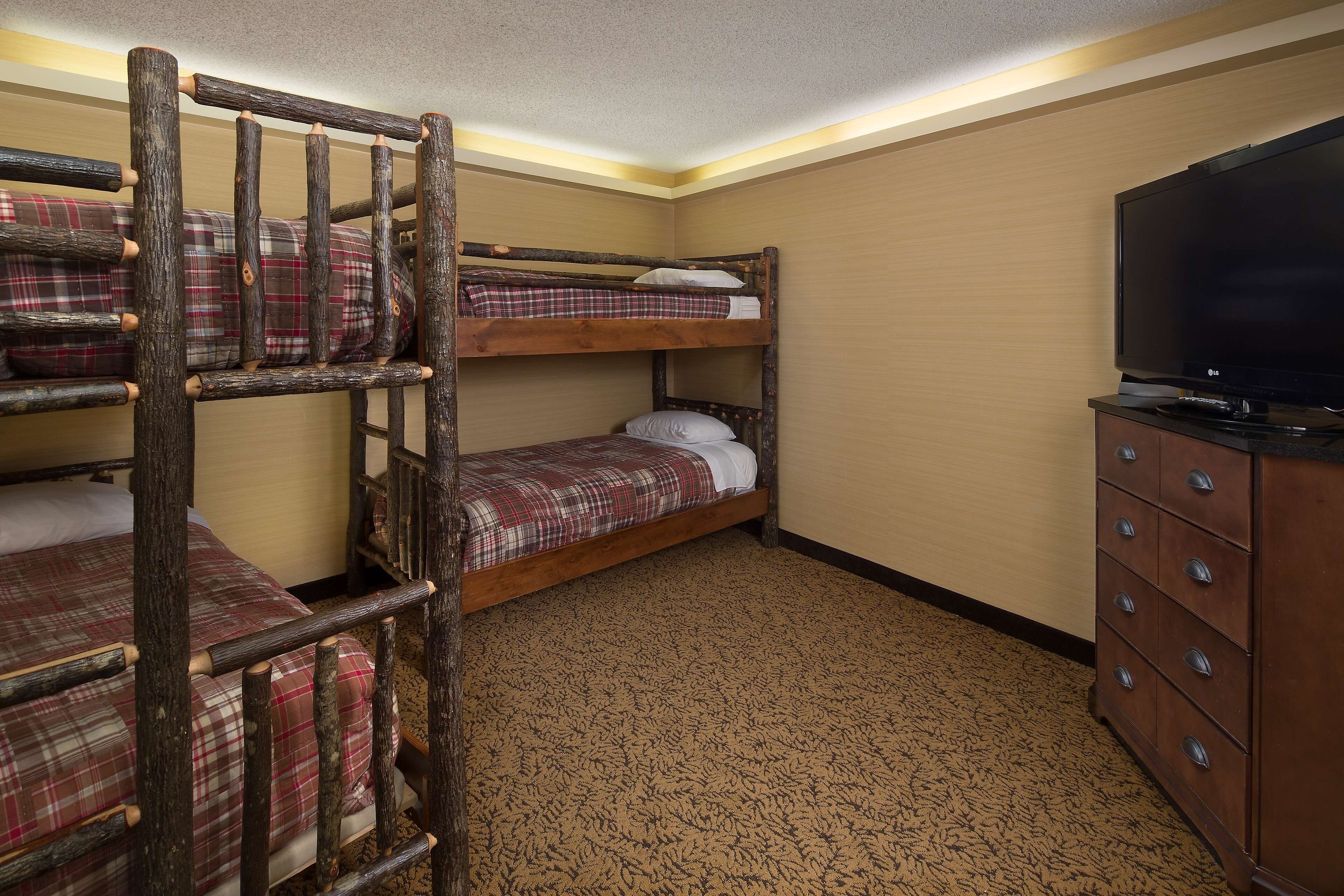 A room with bunk beds, a television, and a dresser.