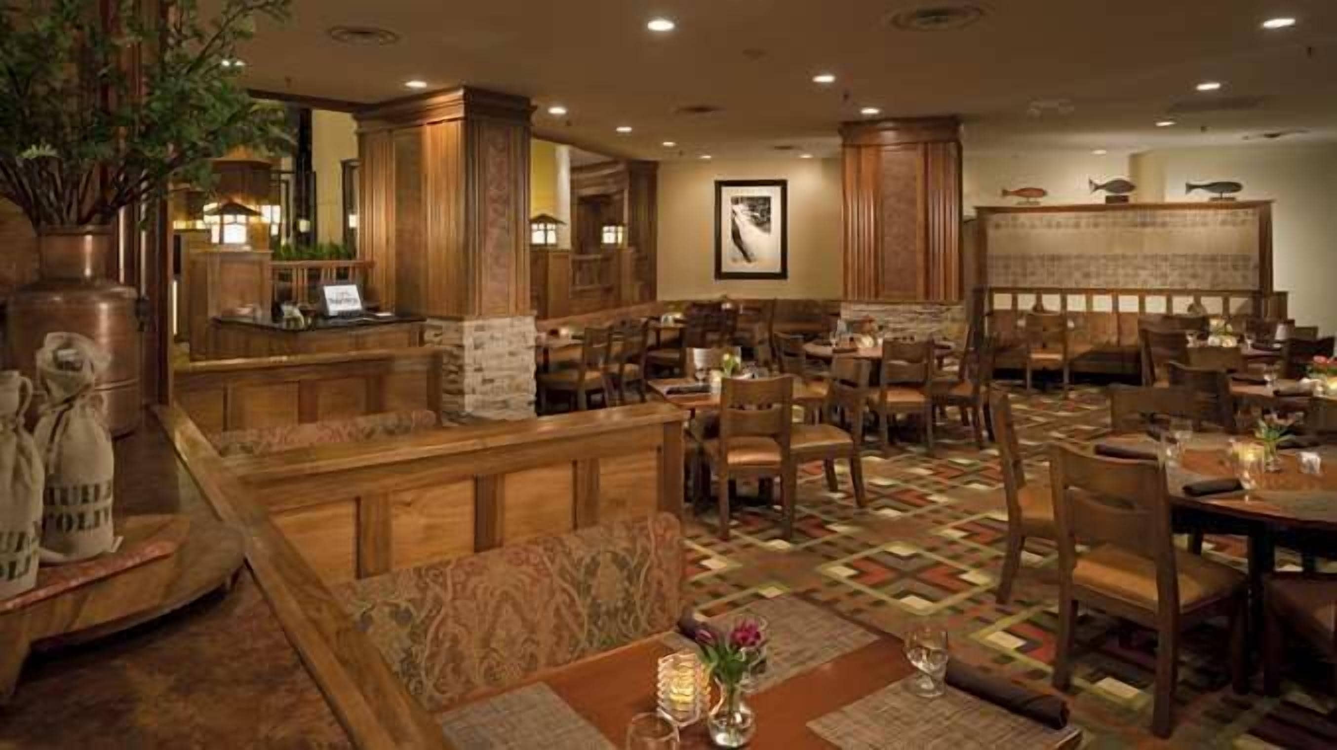 A restaurant with wooden furniture, a patterned floor, and a bar area.