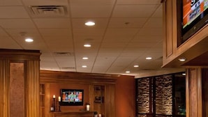 A bar area with wooden furniture, a television, and a stone wall. - The Park Vista - a DoubleTree by Hilton Hotel - Gatlinburg (Gatlinburg)
