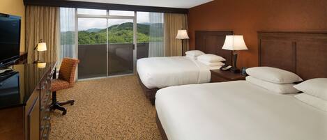 A hotel room with two beds, a TV, a chair, and a view of a mountainous landscape.