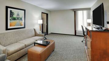 Une chambre d’hôtel équipée d’un canapé, d’une table basse, d’une télévision, d’un bureau et d’une lampe.