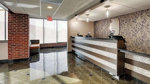 A reception area with a counter, a bench, and a patterned wall. - Drury Inn & Suites Springfield IL (Springfield)