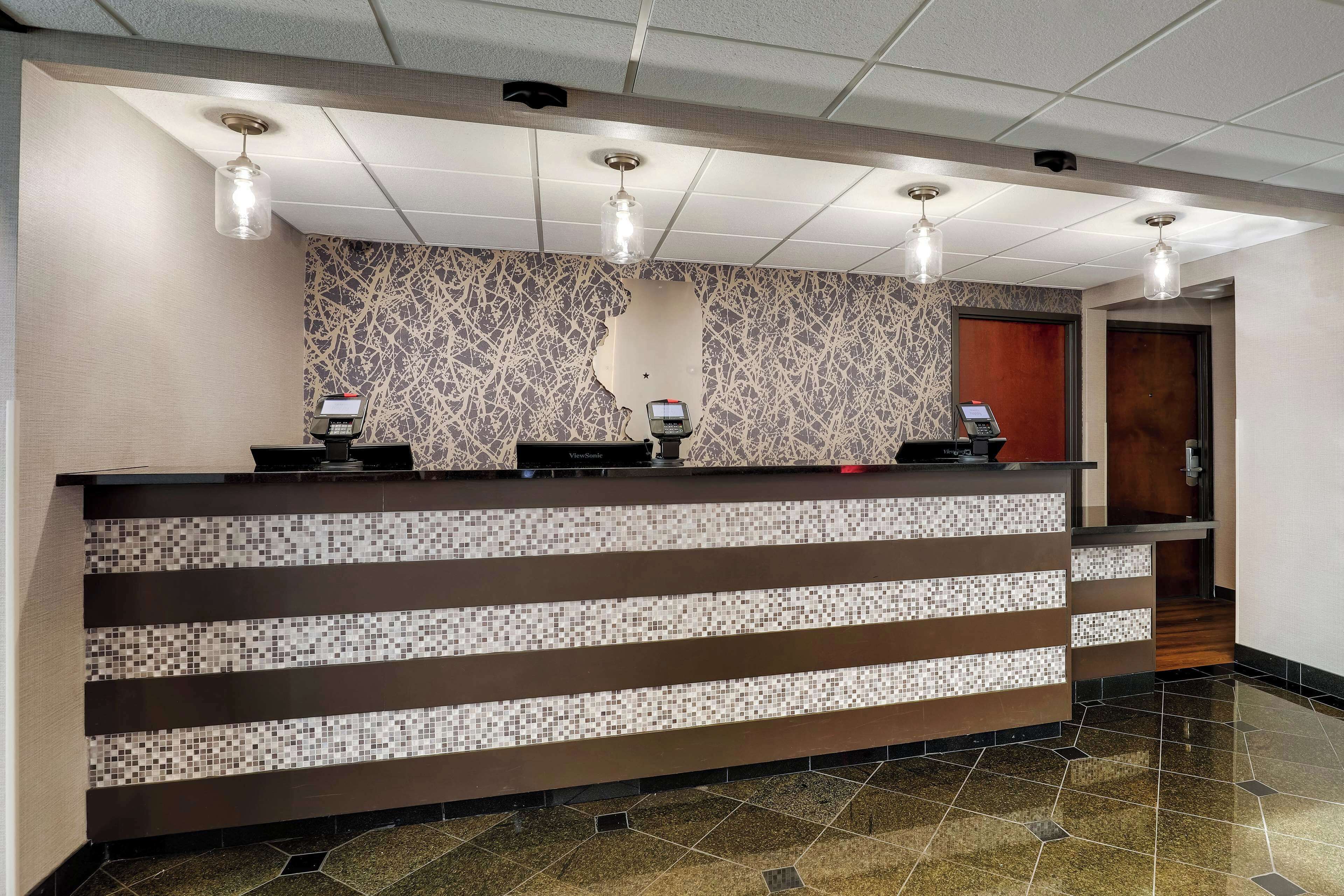 A reception desk with a mosaic tile design, three pendant lights, and a telephone.