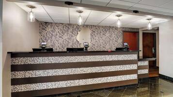 A reception desk with a mosaic tile design, three pendant lights, and a telephone.