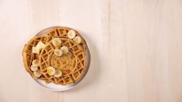 A plate of waffles with banana slices and syrup.