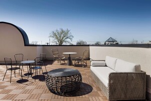 Terraza en la azotea con una mesa redonda, sillas y un sofá.