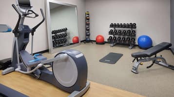 A gym with cardio equipment, weightlifting dumbbells, exercise balls, and a bench.