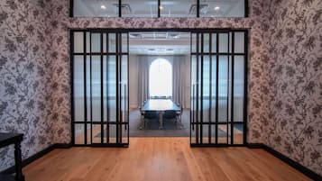 A conference room with a long table, wooden flooring, and floral wallpaper.