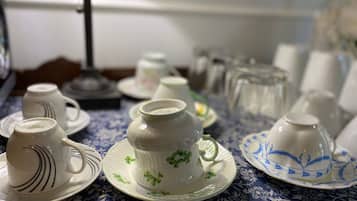 Una mesa con varias tazas y platillos de cerámica blanca, algunos con motivos florales, sobre un mantel azul estampado.