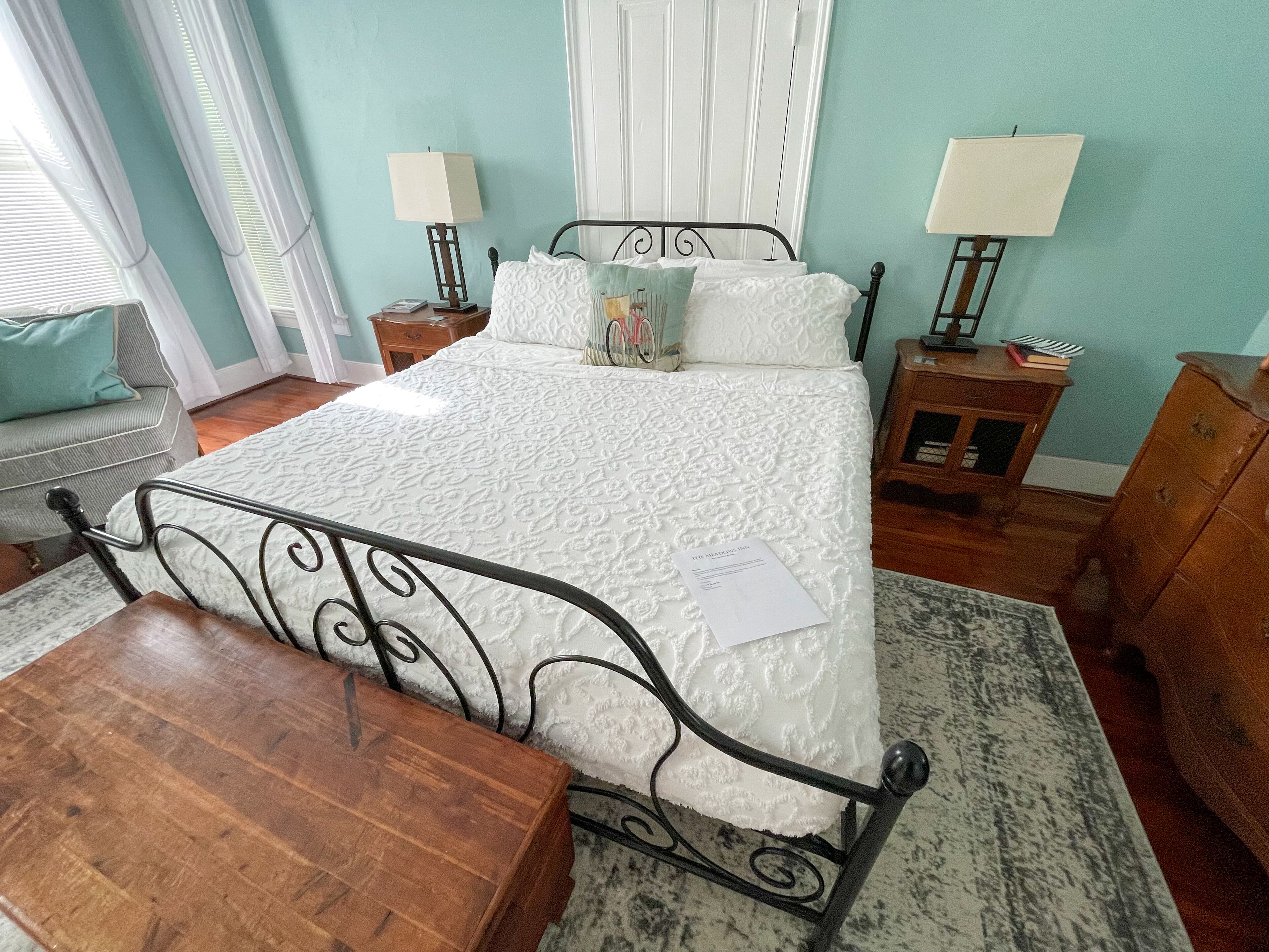 A neatly arranged bedroom with a bed, two bedside tables, a wooden chair, and a dresser.