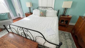 A neatly arranged bedroom with a bed, two bedside tables, a wooden chair, and a dresser.