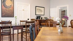 A dining area with a wooden table and chairs, a vase with flowers, and artwork on the walls. - Meadows Inn Bed & Breakfast (New Bern)