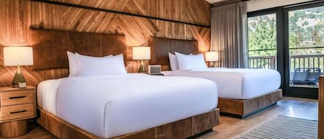 A hotel room with two beds, wooden paneling on the walls, a large window with a view, and a balcony.