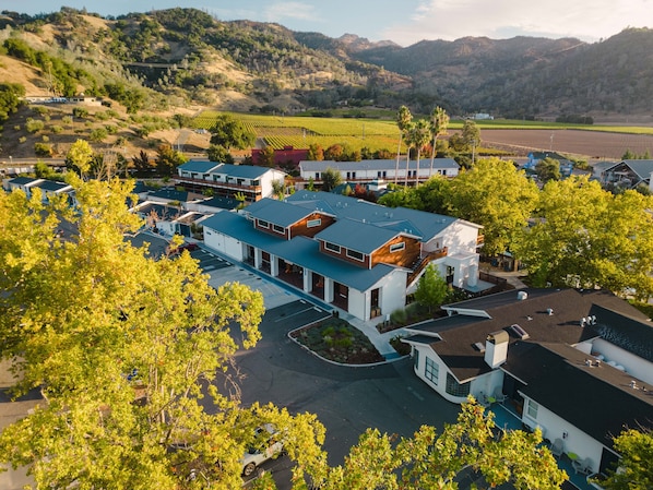 Um edifício moderno de vários andares com um pátio central, rodeado por vegetação exuberante e uma paisagem montanhosa ao fundo.