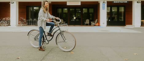 Une personne à vélo devant un bâtiment sur lequel est affiché un panneau indiquant « Inscription ».