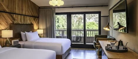 A hotel room with two beds, a desk with a tray of items, a chair, a large window, and a ceiling light.