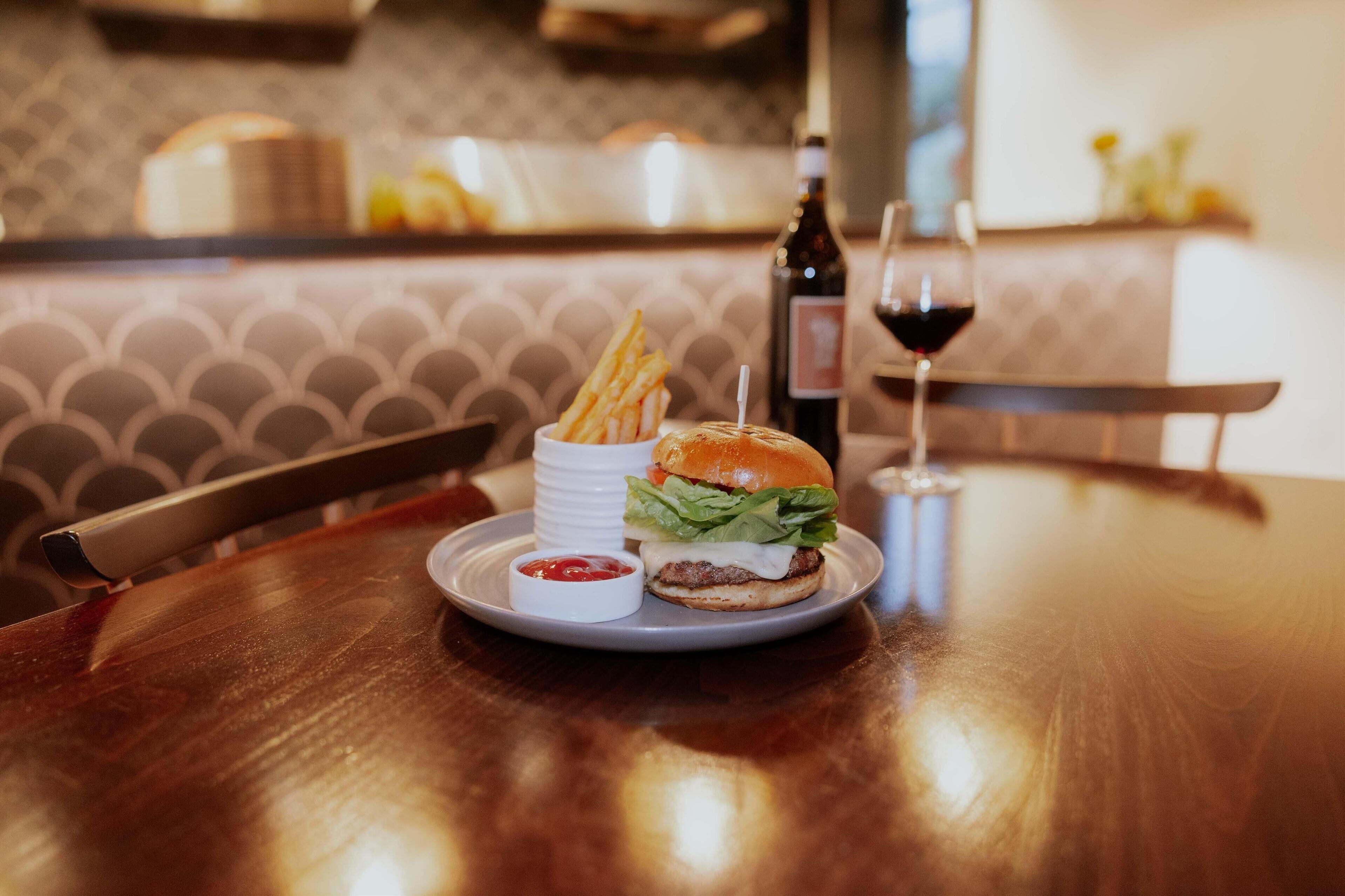 Une table à manger avec un hamburger, des frites et une boisson.