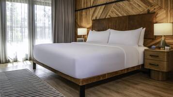 A large bed with white linens, two bedside tables with lamps, and a wooden headboard.