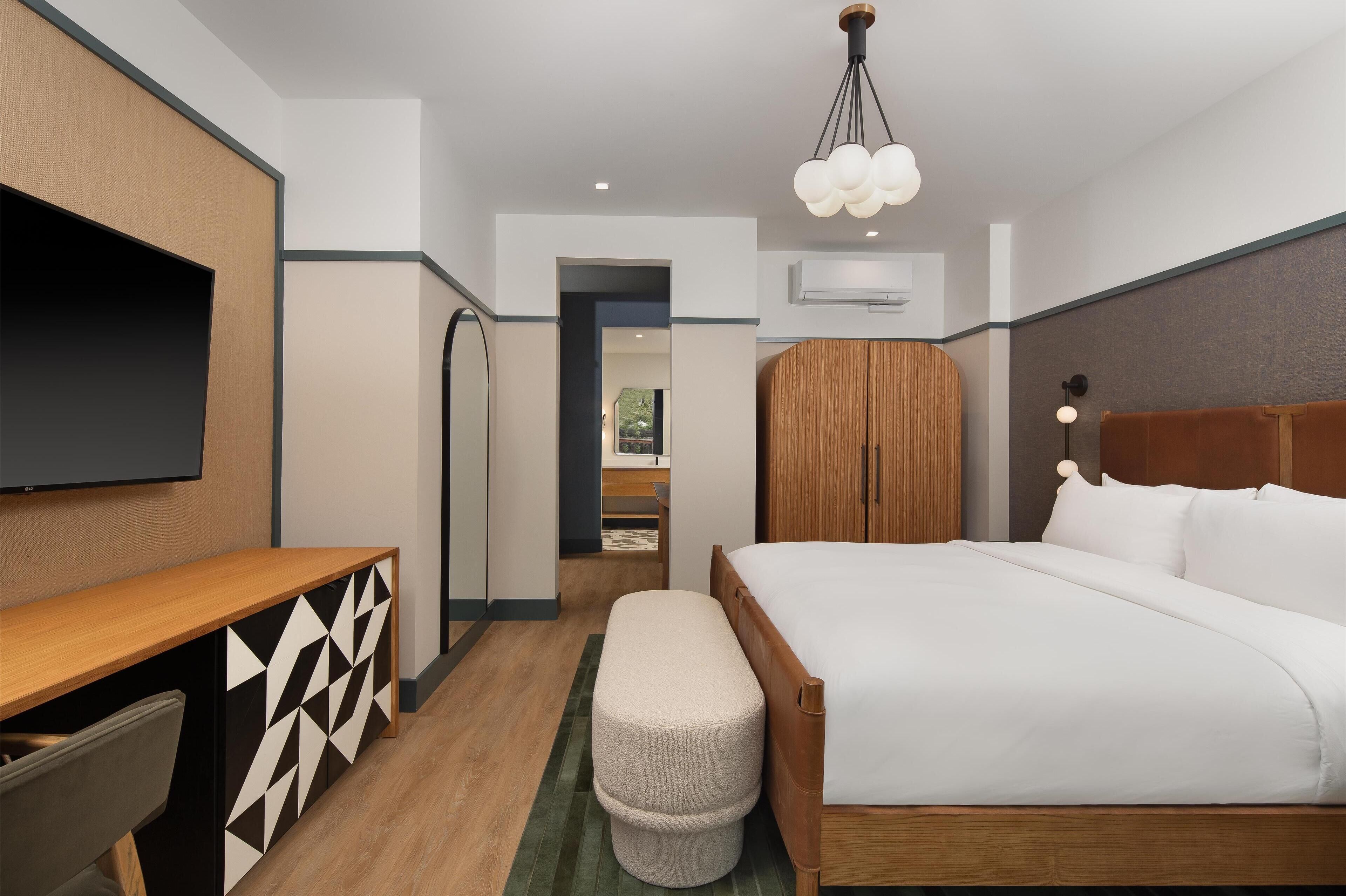 A hotel room with a bed, a desk, a television, and a wardrobe.
