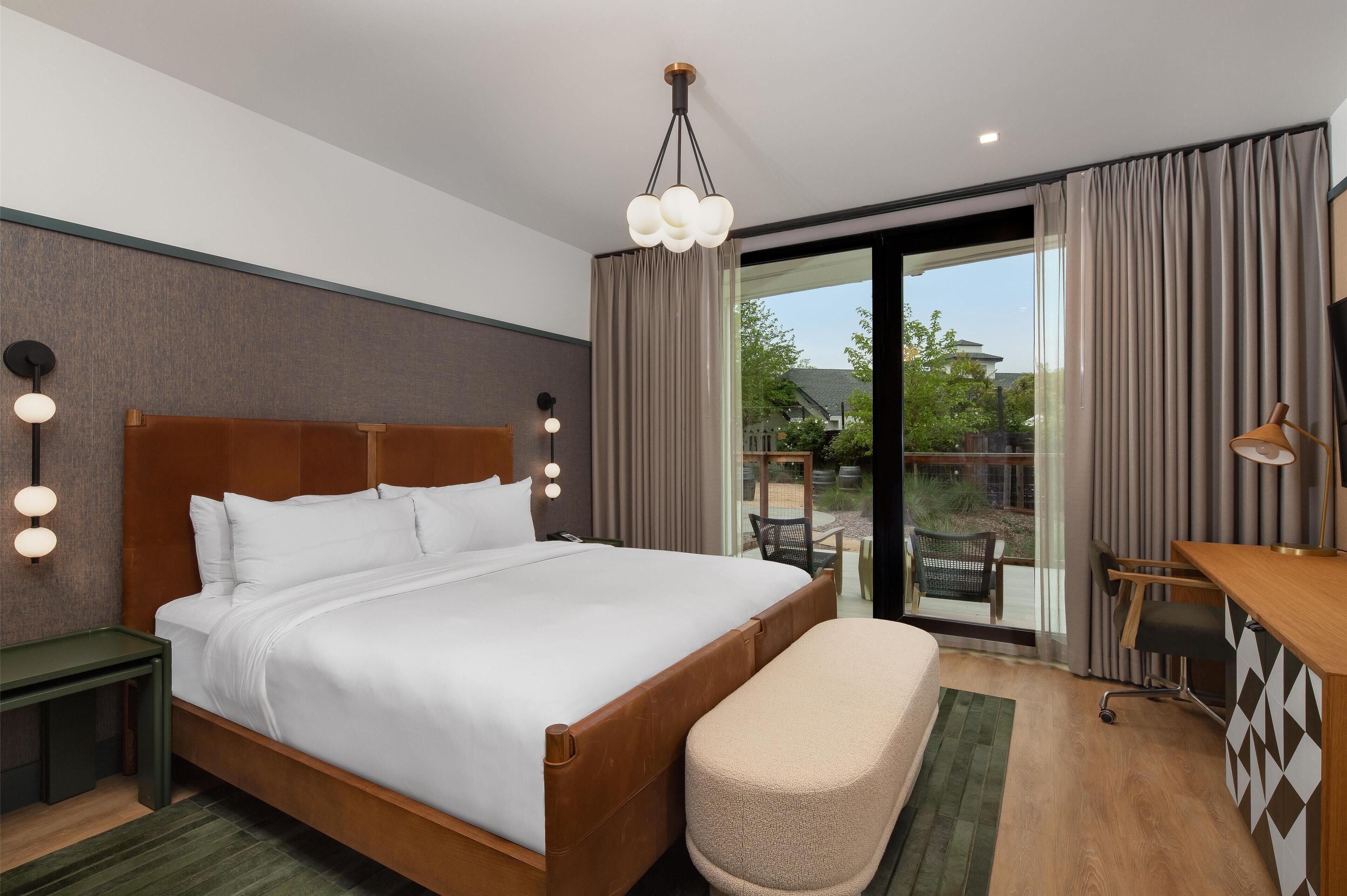 Ein modernes Hotelzimmer mit einem großen Bett, einem Schreibtisch und Blick ins Freie.