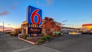 A motel sign with the number 6, a restaurant named 'Angelina's Grill & Bar', and a building with a red roof. - Motel 6 Fort Bragg, CA (Fort Bragg)