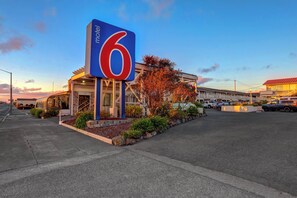 A motel with a prominent '6' sign, a covered parking area, and a building with a red roof. - Motel 6 Fort Bragg, CA (Fort Bragg)