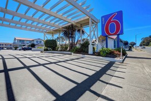 A motel with a large '6' sign, a covered parking area, and a clear sky. - Motel 6 Fort Bragg, CA (Fort Bragg)