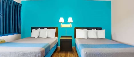 Une chambre d’hôtel avec deux lits, une table de chevet et une lampe fixée au mur.